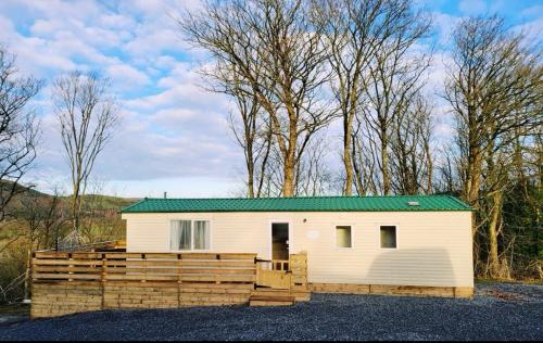 a small white building with a green roof at FAB Caravan Holiday Home in Colmonell