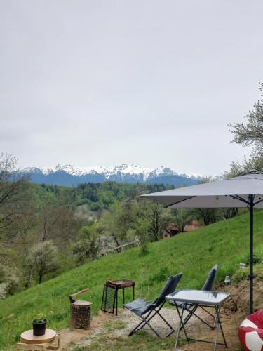 a table and two chairs and an umbrella on a hill at The Sun Chalet by Touch the Sky in Moieciu de Jos