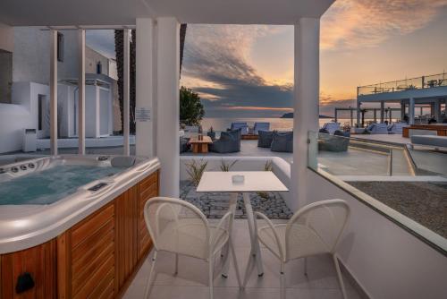 a balcony with a hot tub and a table and chairs at Kantouni Beach Boutique Hotel in Panormos Kalymnos