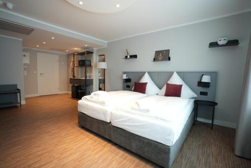 1 dormitorio con 1 cama grande con sábanas blancas y almohadas rojas en Boutique Kaiser - Hotel & Apartments, en Frankfurt