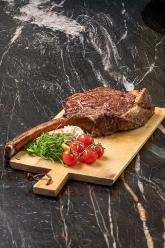 a steak on a cutting board with vegetables on a table at Strandhotel Ahlbeck in Ahlbeck