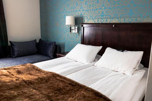 a bedroom with a large bed and a couch at Vimmerby Stadshotell, WorldHotels Crafted in Vimmerby