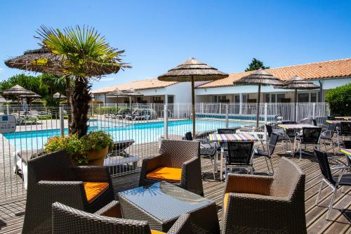 un patio avec des chaises et des tables ainsi qu'une piscine dans l'établissement Hôtel de Ré, "The Originals Boutique", à Sainte-Marie de Ré