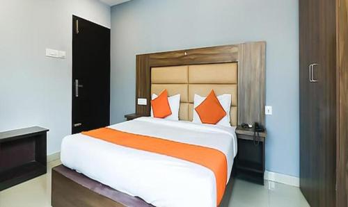 Queens Residency - Kochi في إرناكولام: غرفة نوم مع سرير كبير مع وسائد برتقالية