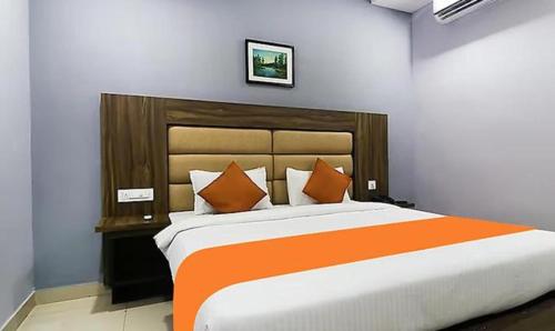 - une chambre dotée d'un grand lit avec des oreillers orange et blancs dans l'établissement Queens Residency - Kochi, à Ernakulam