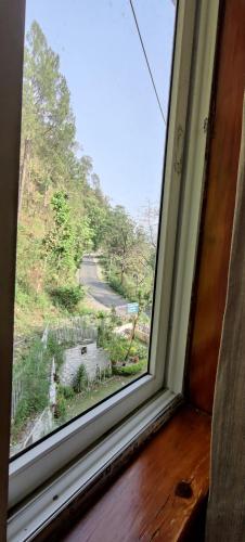 a window in a room with a view of a road at DreamCatcher By Samyati Hotels and Resorts in Bhīm Tāl