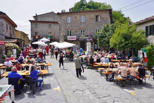 a crowd of people sitting at tables in a street at La Casetta in Montefegatesi