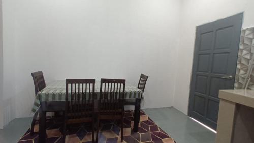 a dining room with a table and two chairs and a door at Family PCB Homestay in Kota Bharu