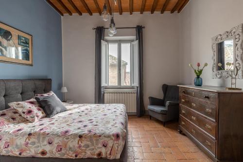 a bedroom with a bed and a dresser and a chair at La sosta di Arrigo in Buonconvento