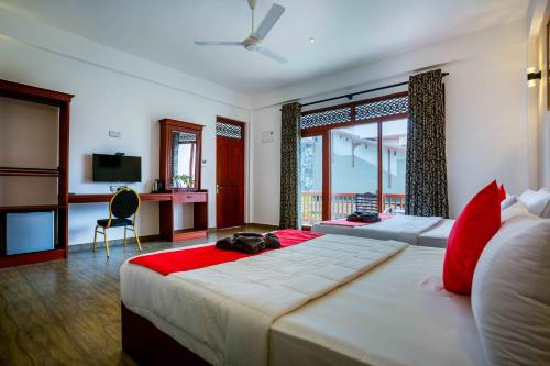 a large bedroom with two beds and a desk at Polhena Grand Resort & Banquet in Matara