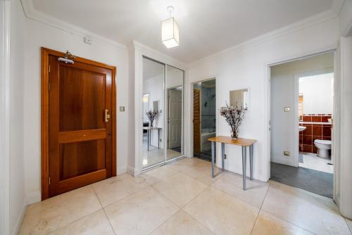 a hallway with a wooden door and a table at Terrific 2 Bed 2 Bath Apt with gym & roof terrace -12 mins from Central London in London
