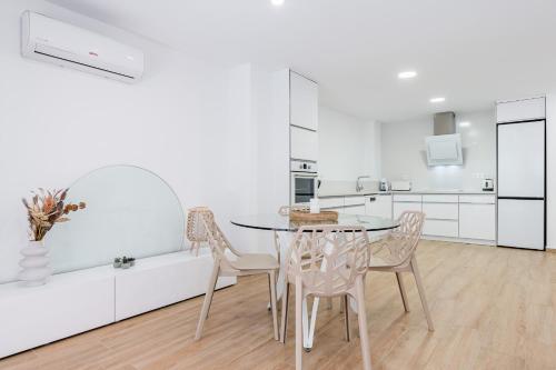 a white kitchen with a table and chairs at Apartamento Sunrise Chapaprieta in Torrevieja