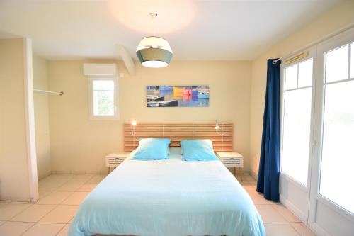 a bedroom with a large bed with two blue pillows at Villa berges landaises location vacances spacieuse Villa avec piscine chauffée capbreton in Capbreton