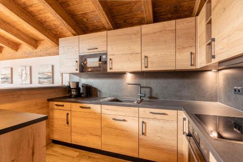 a kitchen with wooden cabinets and a sink at Tauernlodges Uttendorf by ALPS RESORTS in Uttendorf