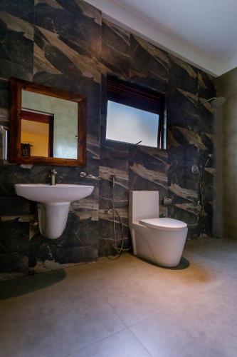 a bathroom with a sink and a toilet and a mirror at Polhena Grand Resort & Banquet in Matara