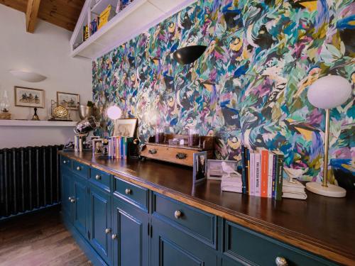 a kitchen with blue cabinets and a colorful wall at Balsoon Lodge in Navan
