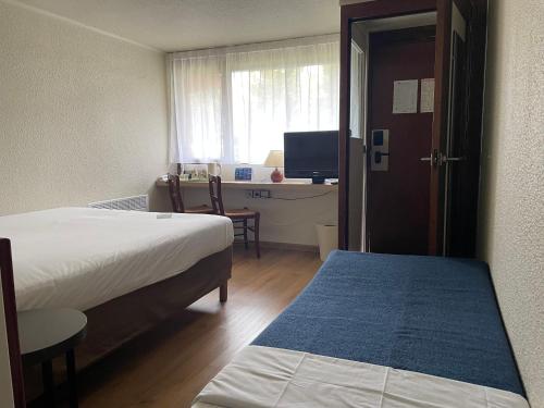 a bedroom with two beds and a desk with a television at Campanile Rouen Nord - Mont-Saint-Aignan in Mont-Saint-Aignan