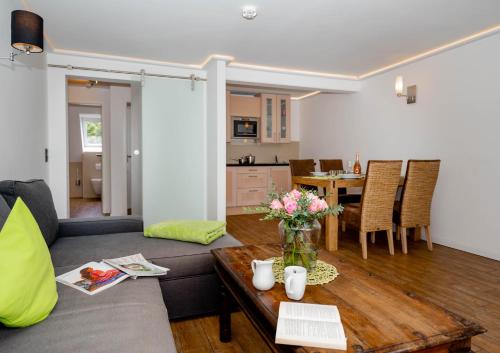 ein Wohnzimmer mit einem Sofa und einem Tisch mit Blumen in der Unterkunft Ferienwohnung Di Südlöner in Westerland