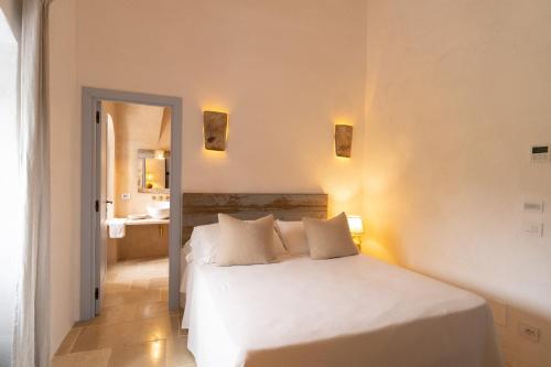 a bedroom with a white bed and a bathroom at Masseria Soluco in Monopoli