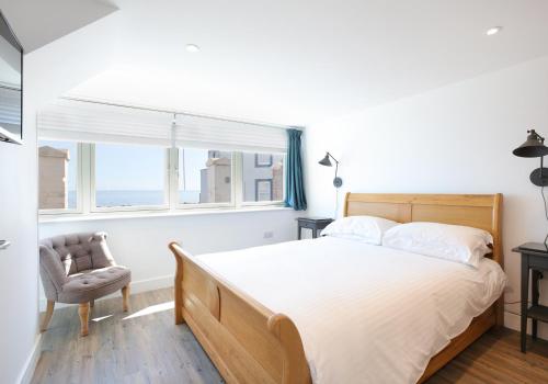 1 dormitorio con 1 cama, 1 silla y 1 ventana en Old Coastguard Station, en Dunbar