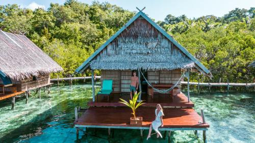 a woman is standing on a wooden dock in the water at Methos Homestay - Raja Ampat in Yennanas Besir