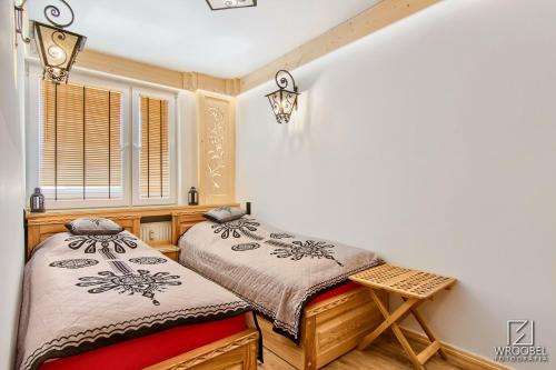2 camas individuales en una habitación con ventana en Apartament Zakopane utrzymany w stylu góralskiej chaty, en Zakopane