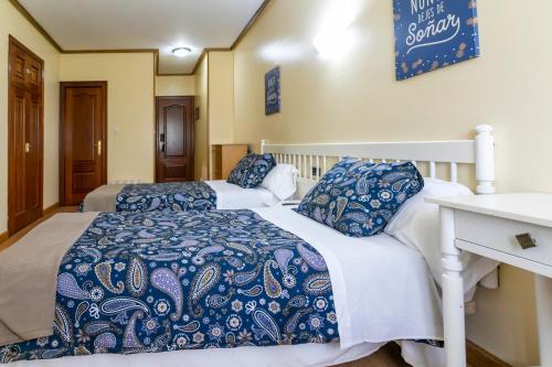 Hotel América Ferrol في فيرول: سريرن مع ملاءات زرقاء وبيضاء في الغرفة