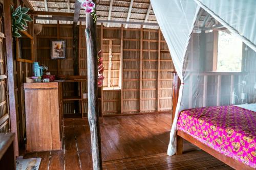Methos Homestay - Raja Ampat في Yennanas Besir: غرفة نوم بسرير في غرفة ذات أرضيات خشبية