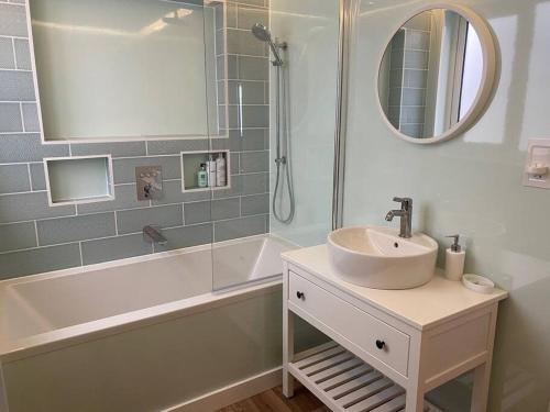 een badkamer met een wastafel, een bad en een spiegel bij 55 High Street in Hastings