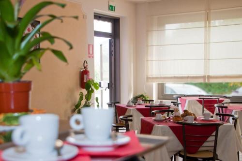 un restaurante vacío con mesas y sillas rojas y una planta en Hotel Residence Vigone, en Vigone