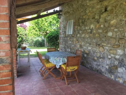 eine Terrasse mit einem Tisch, Stühlen und einer Steinmauer in der Unterkunft CASA INDIPENDENTE con giardino in Castiglione del Lago
