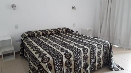 ein Bett mit einer schwarz-weißen Decke drauf in der Unterkunft LA ESQUINA DE LA FLOR in Campo Quijano