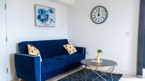 a blue couch in a living room with a table at Lovely 2 bed Penthouse in Loughton central location in Loughton