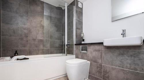 ein Badezimmer mit einer Badewanne, einem WC und einem Waschbecken in der Unterkunft Lovely 2 bed Penthouse in Loughton central location in Loughton