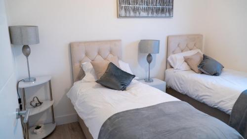 a bedroom with two beds and two lamps in it at Lovely 2 bed Penthouse in Loughton central location in Loughton