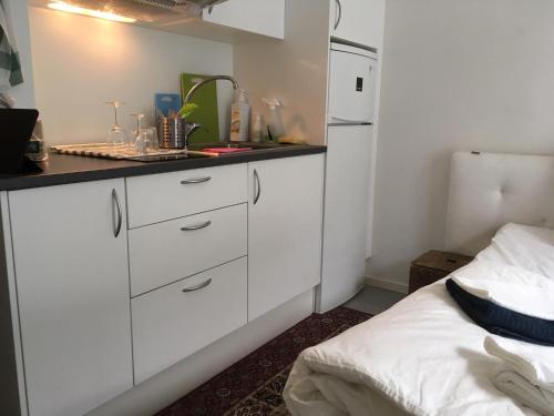 a kitchen with white cabinets and a bed in a room at Beautiful 1- Bed Studio in Sollentuna in Sollentuna