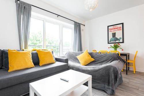 ein Wohnzimmer mit einem grauen Sofa und gelben Kissen in der Unterkunft Central Dublin Apartment Near Guinness & Heuston Station in Dublin