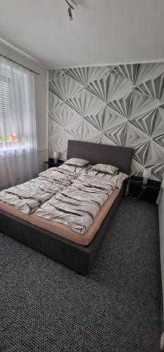 a large bed in a bedroom with a wall at Víztorony apartman in Komló