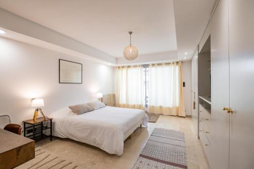 une chambre blanche avec un lit et une fenêtre dans l'établissement Chauvain Résidence, à Nice