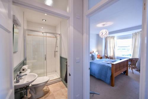 a bedroom with a bed and a bathroom with a sink at 3 bedroom townhouse right on the harbour in Isle of Whithorn