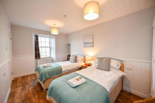 ein Schlafzimmer mit zwei Betten mit Handtüchern darauf in der Unterkunft 3 bedroom townhouse right on the harbour in Isle of Whithorn