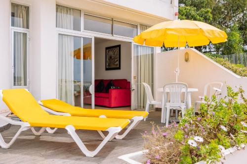 a patio with yellow chairs and an umbrella at Muthu Clube Praia da Oura in Albufeira