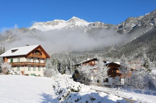 una casa en la nieve con montañas en el fondo en Ferienhaus am Bach, Design und Sauna, en Steinberg am Rofan