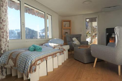 a bedroom with a bed and a couch and windows at HERZLI-CHALET über dem Rheintal mit Schlossblick in Werdenberg