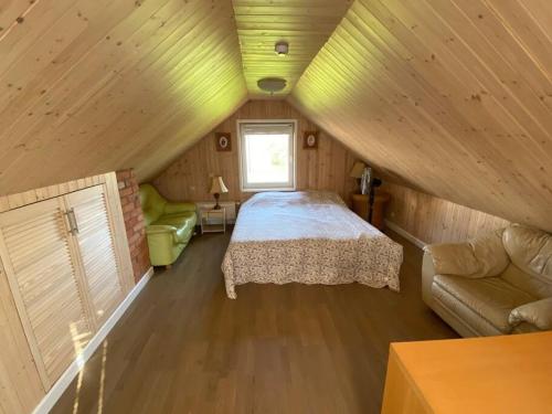 een slaapkamer met een bed en een bank op zolder bij Small Red-Brick House in Kaunas