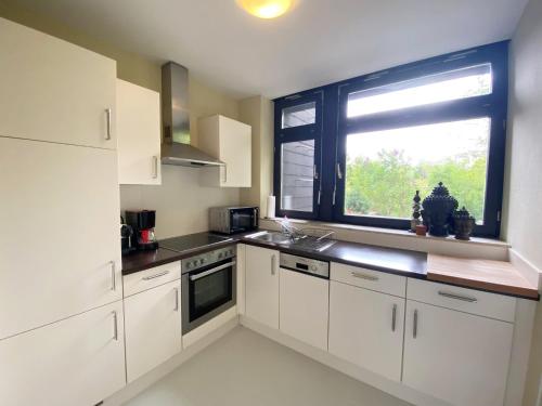 a kitchen with white cabinets and a large window at Gästehaus am Brockeswald in Cuxhaven