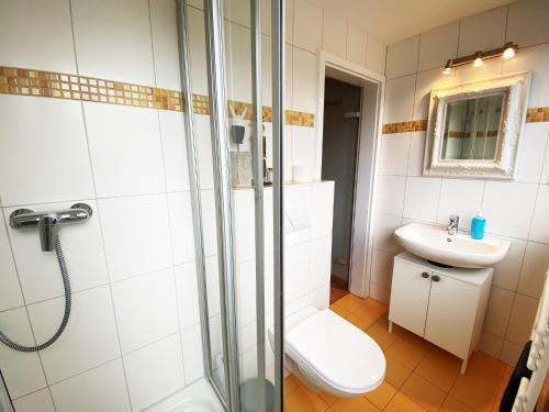 een badkamer met een douche, een toilet en een wastafel bij Gästehaus am Brockeswald in Cuxhaven