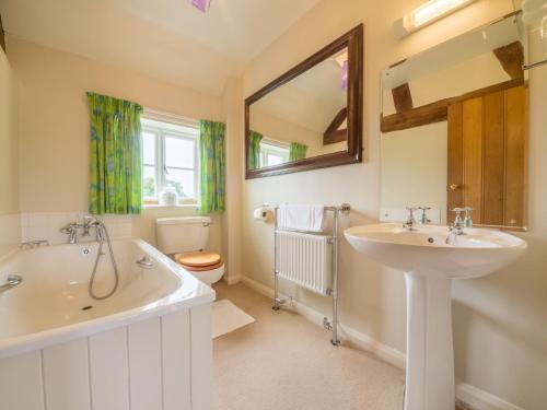 a bathroom with a tub and a sink and a toilet at Bearwood House & Cottage in Pembridge