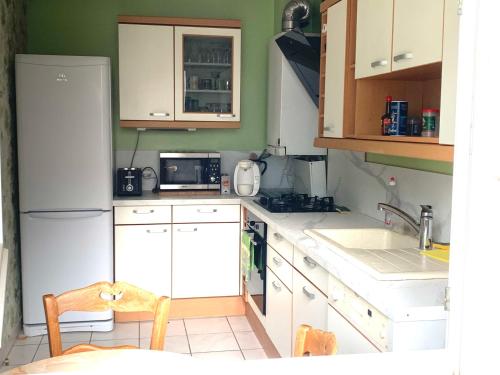 La cuisine est équipée de placards blancs et d'un réfrigérateur blanc. dans l'établissement 80m2-Maison des quais - parking - jardinet, à Rouen
