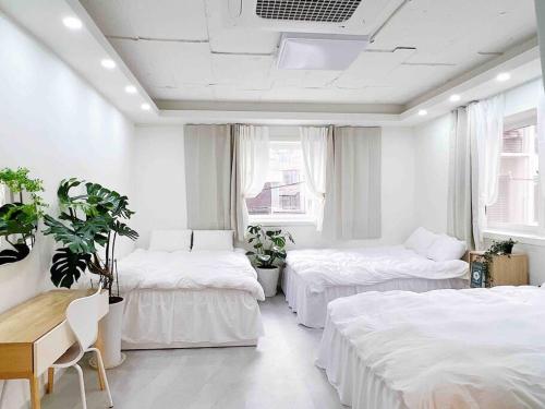a bedroom with two beds and a table and a desk at Near Hongik University Station Suite Room in Seoul